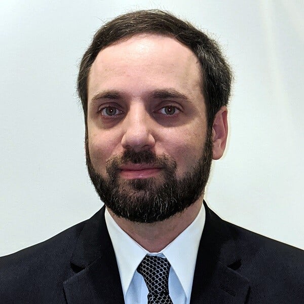Photo of Eric Bragger in a suit and tie, with beard and partial smile.
