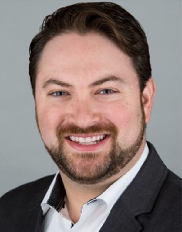 Photo of Brandon Friedman in a suit, with beard and full smile.